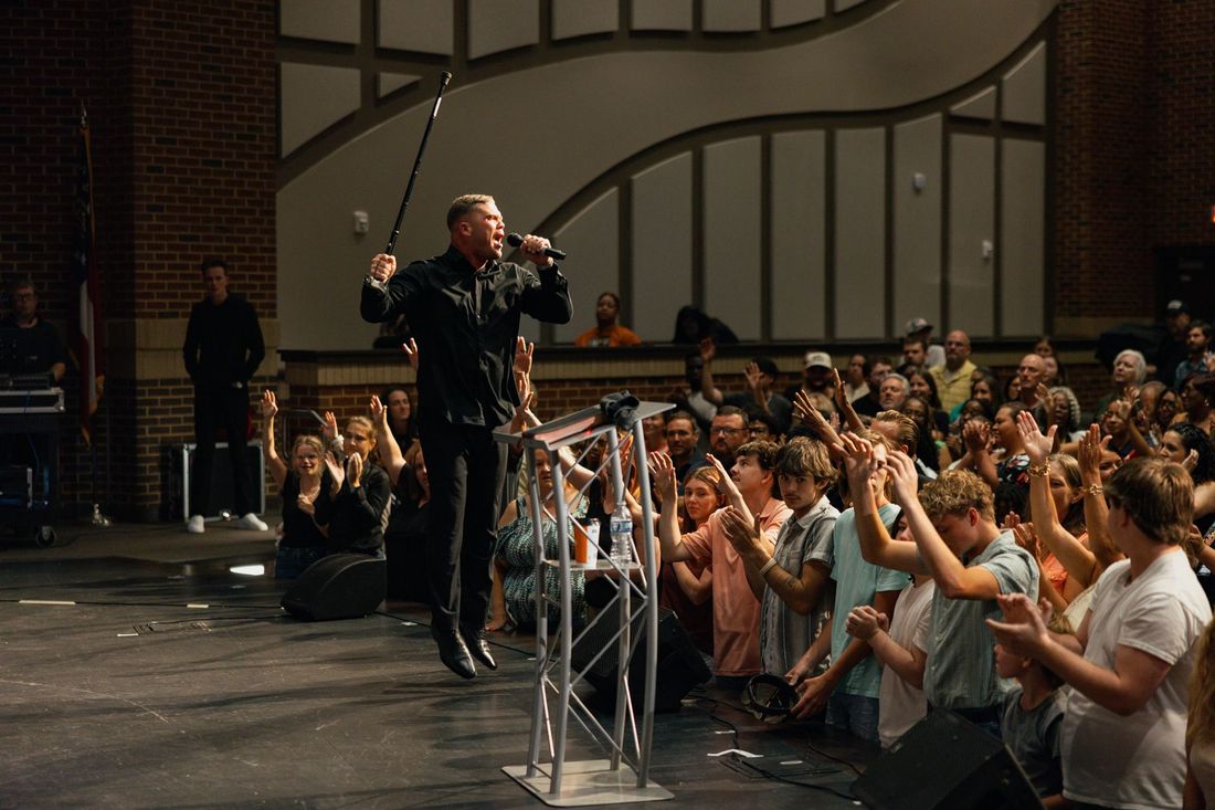 People at the altar with hands raised as a preacher ministers from the stage at Hope Night